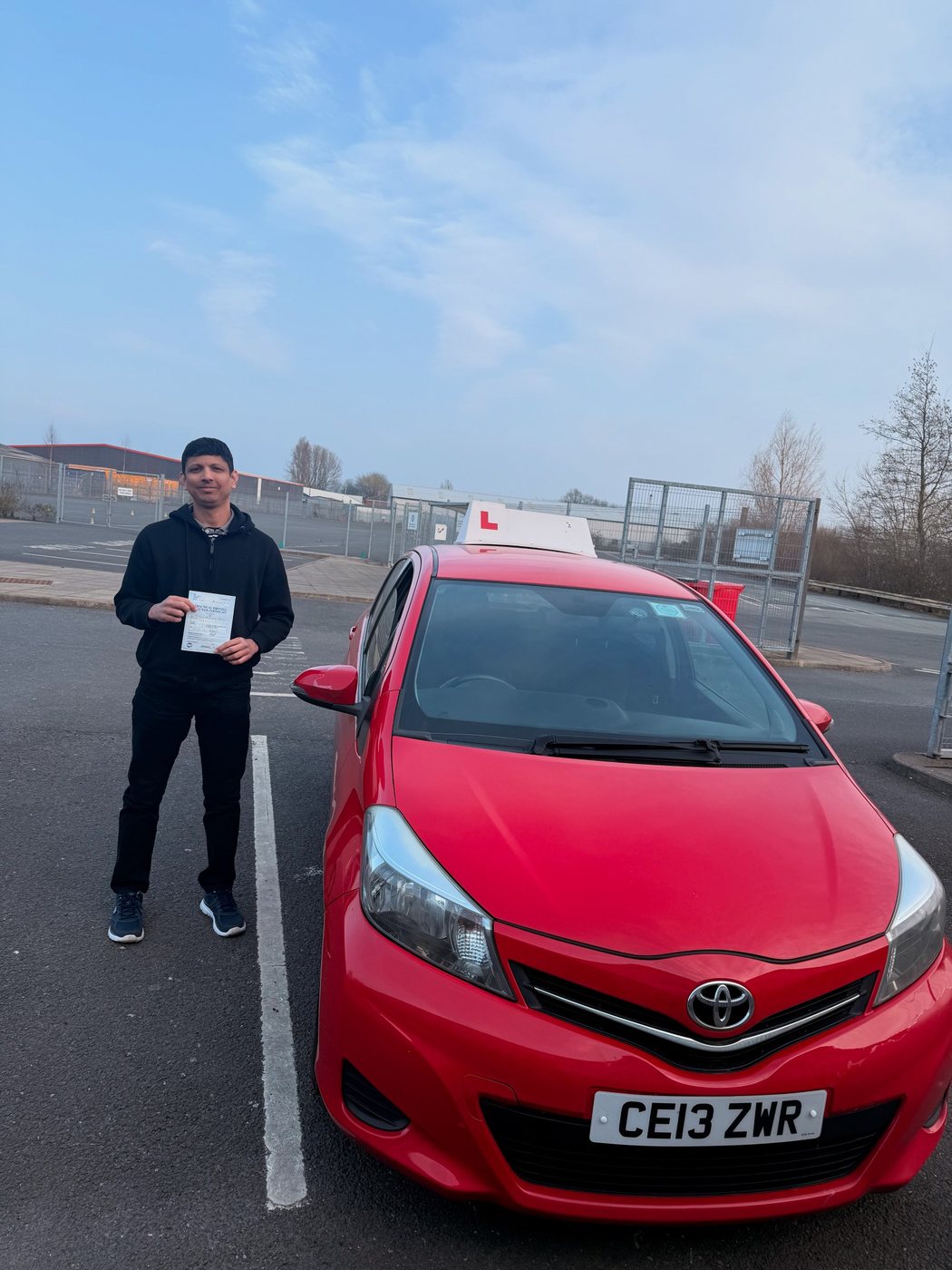 Student celebrating a driving test pass with learner car