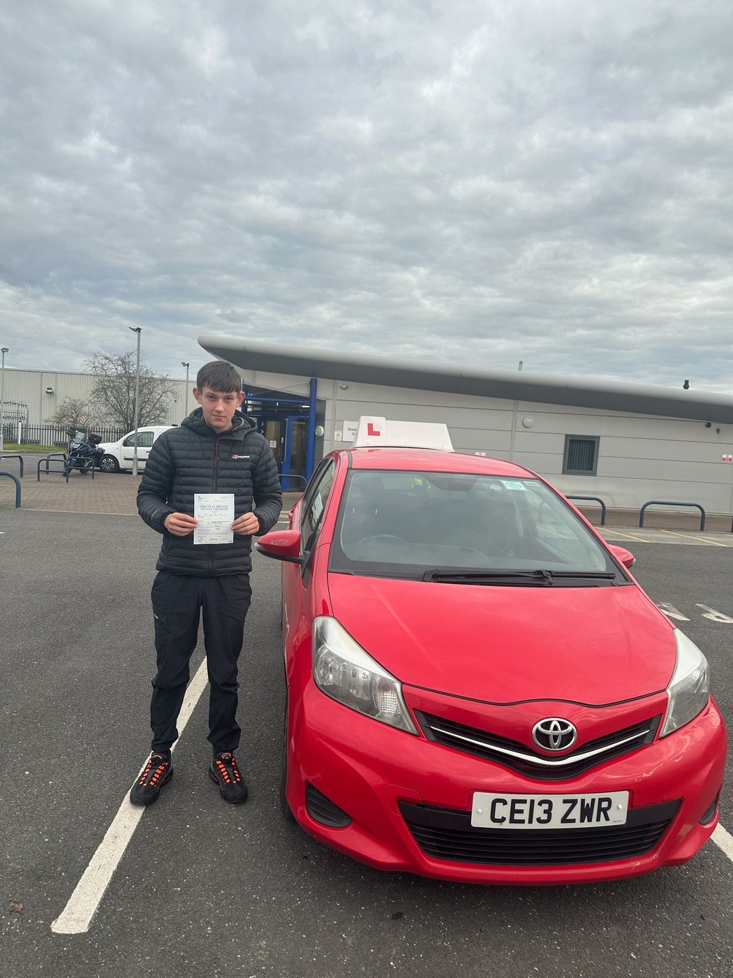 Student celebrating a driving test pass with learner car