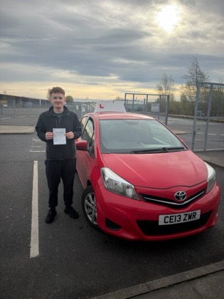 Student celebrating a driving test pass with learner car