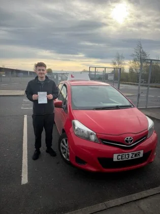Student celebrating a driving test pass with learner car