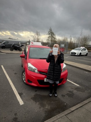 Student celebrating a driving test pass with learner car