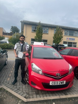 Student celebrating a driving test pass with learner car