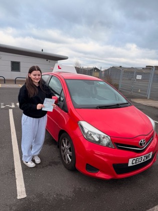 Student celebrating a driving test pass with learner car