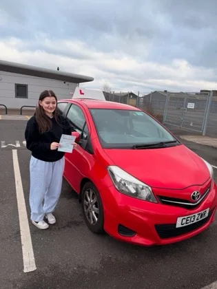 Student celebrating a driving test pass with learner car