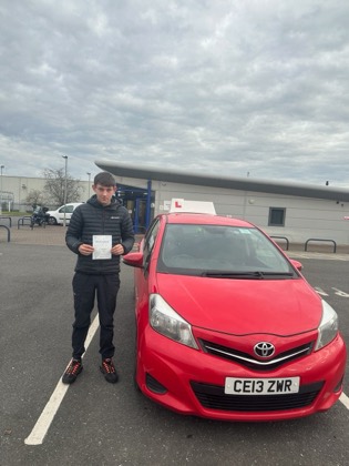 Student celebrating a driving test pass with learner car