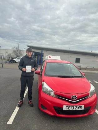 Student celebrating a driving test pass with learner car