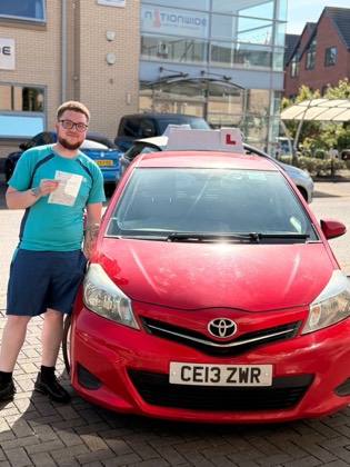 Student celebrating a driving test pass with learner car
