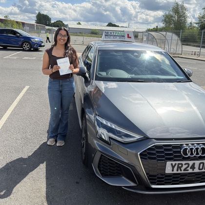 NextPass learner celebrating a driving test pass beside an Audi learner car