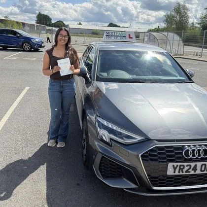 NextPass learner celebrating a driving test pass beside an Audi learner car